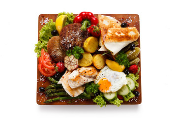 Various meat and vegetables served on cutting board