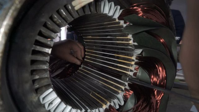 Mechanic stacks coils of the stator. Electric motor repairing.