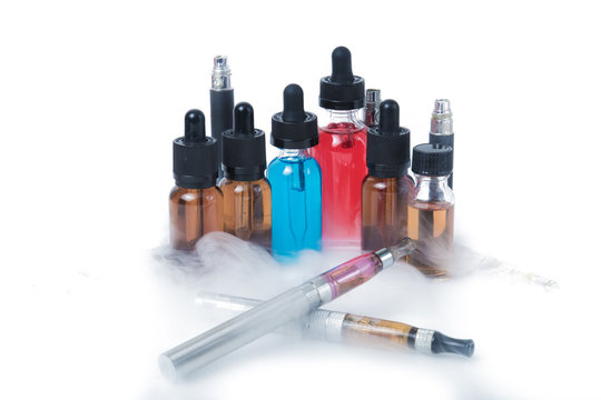 Two electronic cigarettes with glass e-liquid bottles with smoke on white background