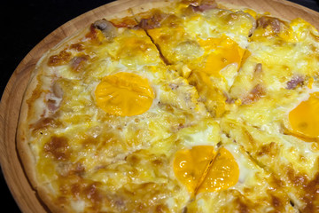 egg with mushroom and ham pizza on the wood tray and black counter bar for dinner food in the restaurant on nature light