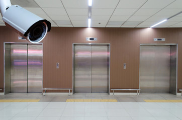 cctv security camera with closed metal office building elevator doors in modern building, security...