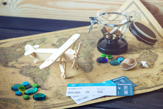 Toy wooden plane on a world map with colored stones and shells from the sea in a retro style.