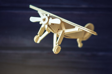 Fototapeta na wymiar Wooden toy airplane flies on a dark background in retro style