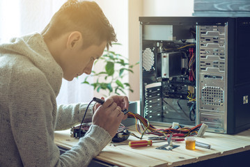 Man repairman is trying to fix using the tools on the computer that is on a workplace in the office