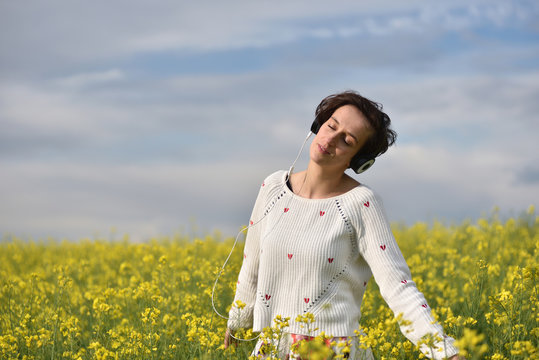 Beautiful Caucasian girl listening to music with headphone in the outdoors