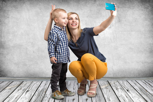 Young mother and little son are photographed on a mobile phone making selfie.Stylish,trendy,modern