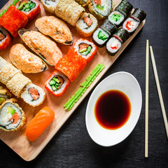 Sushi rolls, mussels, soy sauce and chopsticks on a black background. Top view. Flat lay. Japanese traditional food