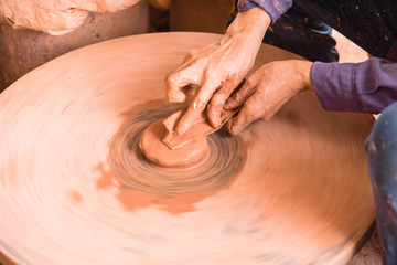 Close-up female hands throwing pottery on the wheel in a clay studio at ceramic village in Vietnam. Hand making, forming clay pot on pottery plate. Artisan making traditional ceramic manually.