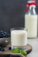 Freshly picked juicy blueberries with green leaves on rustic table and fresh cow milk. Bilberry on wooden Background. Blueberry antioxidant. Concept for healthy eating and nutrition