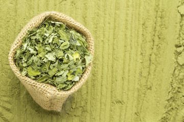 Leaves and moringa powder on wood (long moringa)