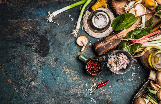 Fresh seasoning and vegetarian organic cooking ingredients for tasty cooking on dark rustic background, top view, place for text. Clean healthy organic vegan or vegetarian food concept