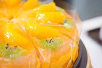Fototapeta na wymiar Sliced of orange and kiwi cake on wooden plate close up.