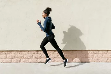 Zelfklevend Fotobehang Side view of female athlete running against wall © Artem Varnitsin
