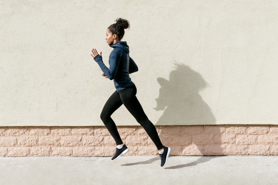 Side view of female athlete running against wall