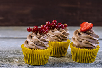 Delicious chocolate cupcakes with berries on white table, top view