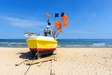 Colorful fishing boat on sandy Sopot beach in sunny day. Baltic sea, Pomerania.  Poland - obrazy, fototapety, plakaty