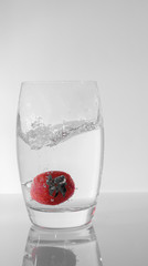 Spritzer im Glas mit Wasser und fallender Erdbeere