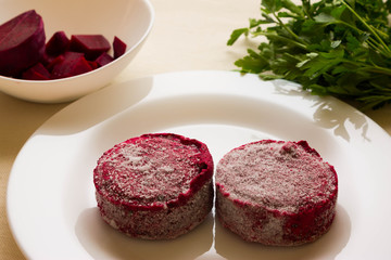 Frozen beet cutlets on a white plate and ingredients. Vegetarian dish.