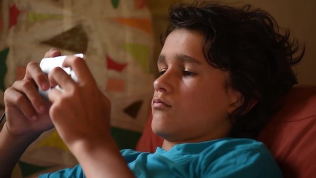 Teenager looking at his smartphone on a sofa