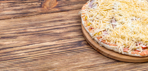 Raw homemade pizza on the wooden table.