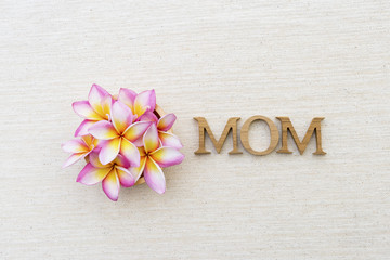 Mother's day concept background, mom wooden letter with beautiful plumeria flower on canvas background