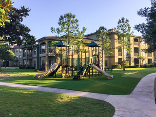 A typical apartment complex building with a central playground swing, stairs in suburban area at...