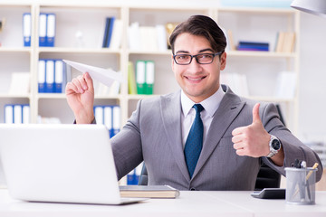 Businessman with paper airplane in office