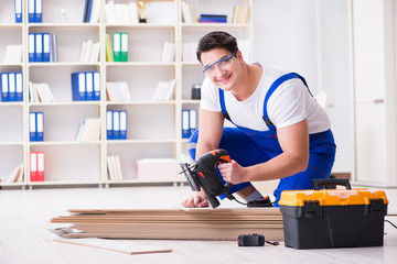 Young worker working on floor laminate tiles