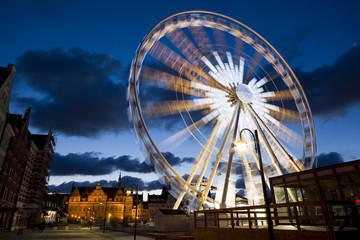 Rotating Ferris wheel located in the Old Town of Gdansk, Poland at night. Green Gate in the background