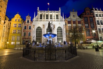 Fototapeta na wymiar Illuminated Neptune Fountain and Artus Court at Long Market (part of Royal Route) in Gdańsk at night, Poland