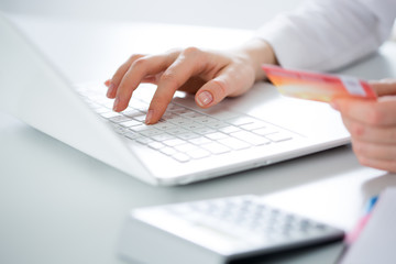 Businessman holding credit card and using laptop.