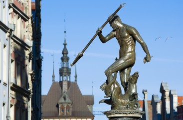 Fototapeta na wymiar Neptune Fountain - symbol of Gdansk, located at Long Market, blurred roof of the Prison Tower in the background, Poland