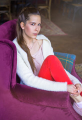 Beautiful girl dreaming about something while sitting in a cafe and looking at window. Young charming woman thinking about new ideas, sitting on an armchair in a modern city bar.