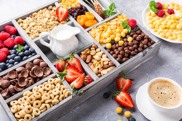 Healthy breakfast with coffee, variety of cold quick cereals and berries in old gray wooden box, selective focus.