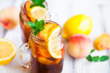 Homemade lemonade with ripe  peaches and fresh mint. Fresh peach ice tea on white wood table. Copy...