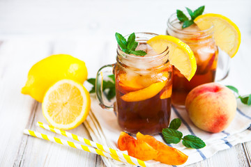 Homemade lemonade with ripe  peaches and fresh mint. Fresh peach ice tea on white wood table. Copy...