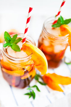 Homemade lemonade with ripe  peaches and fresh mint. Fresh peach ice tea on white wood table. Copy space background.