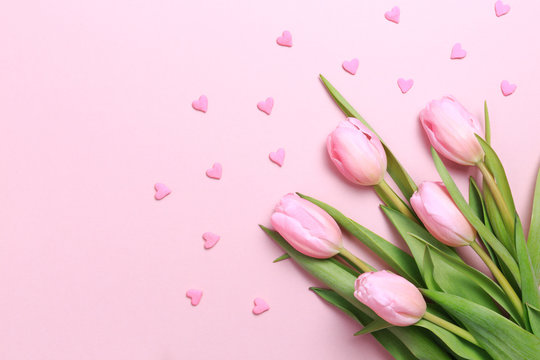 Pink tulips with pink heart sprinkles on the pink background. Flat lay, top view.  Valentines background.