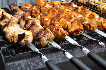 Grilled kebab cooking on metal skewer closeup. Roasted meat cooked at barbecue. Traditional eastern dish, shish kebab. Grill on charcoal and flame, picnic