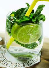 Cold pure carbonated water with lime in a glass on a light background. Selective focus. Vertical.