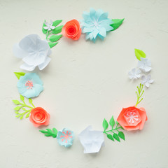 round frame with color paper flowers on the white stucco. Flat lay. Nature concept