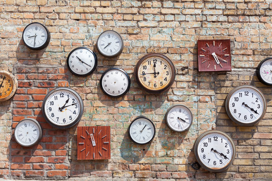  Brick wall background with numerous round and square clocks
