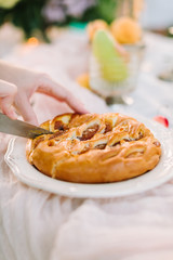 picnic, food, holiday concept - close-up on delicious beautiful apple pie with filling of jam, man hands with a knife cutting appetizing pie, fruit on white tablecloth, selective focus