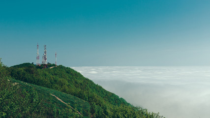 Fototapeta na wymiar Telecommunication towers on top of a mountain against a background of clouds and fog. Mountain landscape. Gelendzhik, North Caucasus, Russia