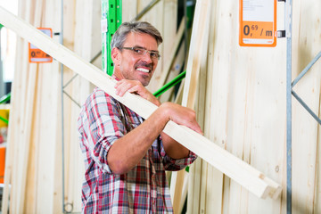 Kunde in der Holzabteilung von Baumarkt sucht Latten für Heimwerker-Projekt