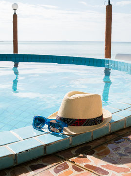 Image of hat and sunglasses by pool
