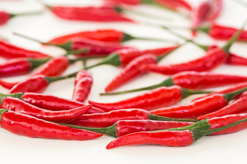 kitchen, food making, popular spices concept - handful of fresh red hot peppers, pods scattered and filled white background, selective focus