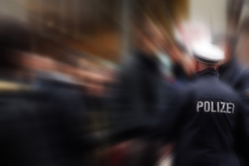 German police officer in action, shot from behind, focus on the jacket with POLIZEI lettering, that...