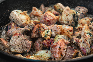 Meat is fried in a frying pan with spices close-up