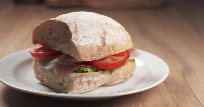 Slide shot of ciabatta sandwich with speck, mazzarella and vegetables, 4k 60fps prores footage